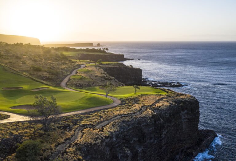 View of Lanai island, manicured green lawn, and cliffs edge leading to ocean.