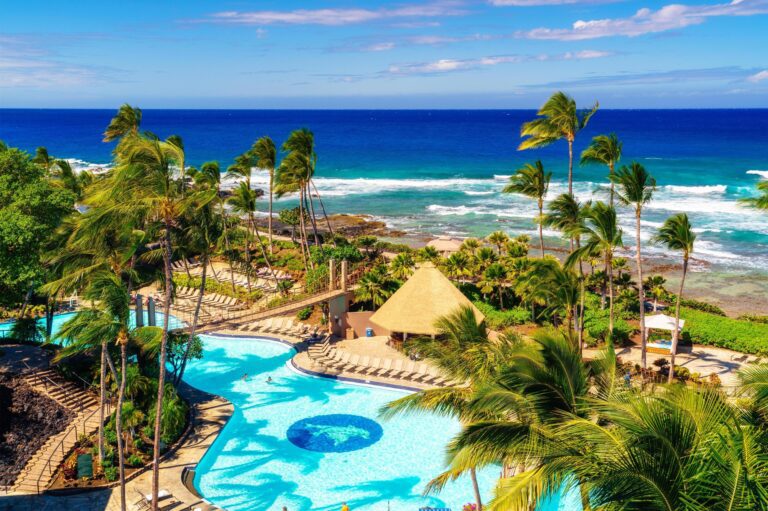 Overview of tropical resort pool with ocean view in background.
