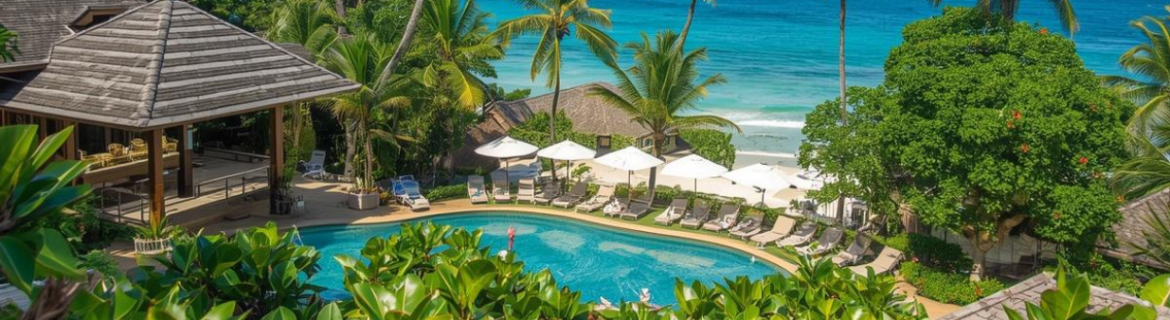 Tropical beach hotel with pool and foliage, next to beach.