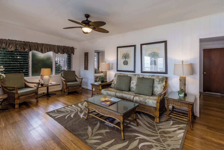 Kaikea Hale Oceanfront condo, image of living room with wood flooring andf tropical wood furniture.