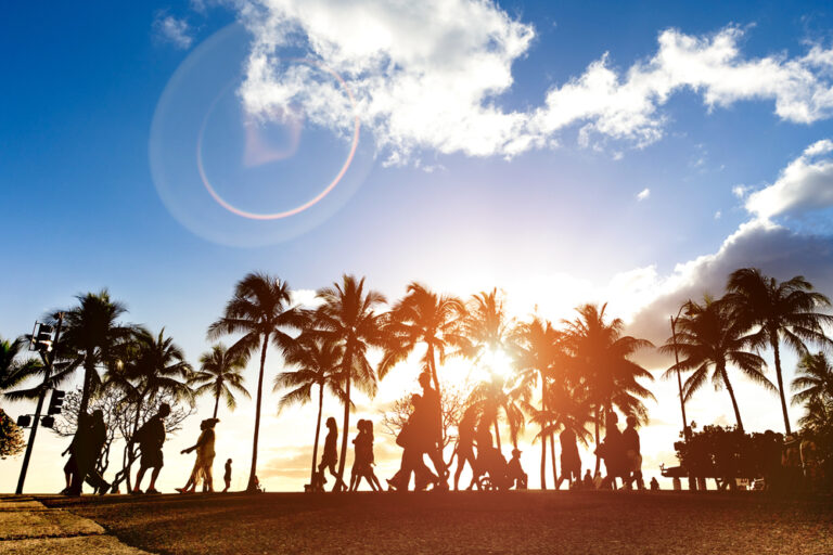 Silhouettes of people walking on sidewalk in Waikiki