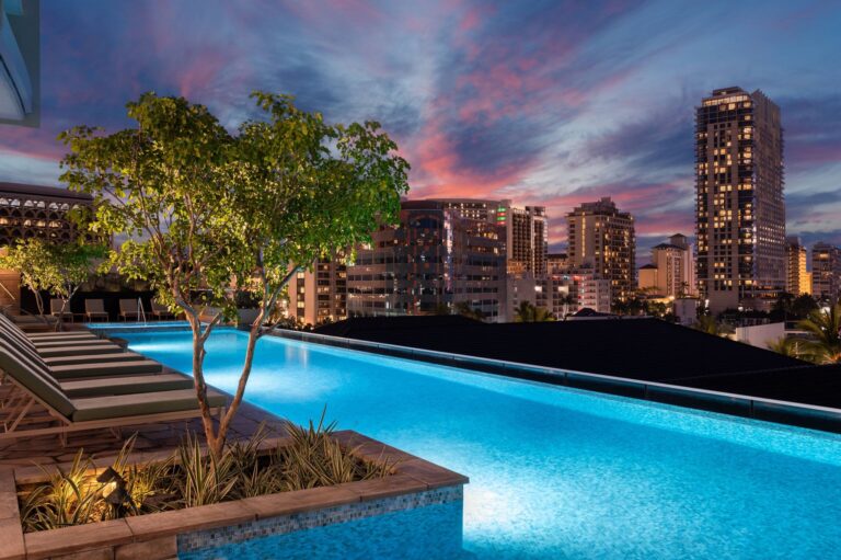 resort pool lit up at night, pink sunset clouds